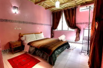 a bedroom with a bed in a room with pink walls at Kasbah Restaurant Amazir in Tinerhir
