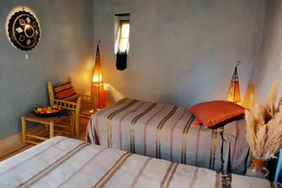 a bedroom with two beds and a chair and a table at Riad Cascades d'Ouzoud in Ouzoud