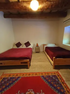 a bedroom with two beds and a rug at Kasbah Auberge Bassou in Nkob