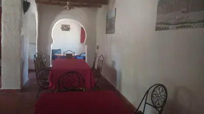 a dining room with a red table and chairs at Kasbah Auberge Bassou in Nkob