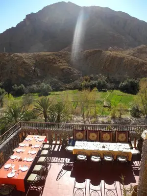 a patio with tables and chairs with a view of a mountain at Maison d'Hôte Valentine in Tinerhir