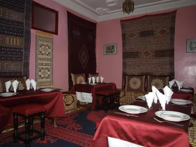 a dining room with two tables with red table cloths at Maison d'Hôte Valentine in Tinerhir