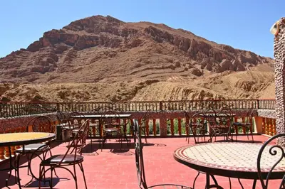a patio with tables and chairs and a mountain at Maison d'Hôte Valentine in Tinerhir