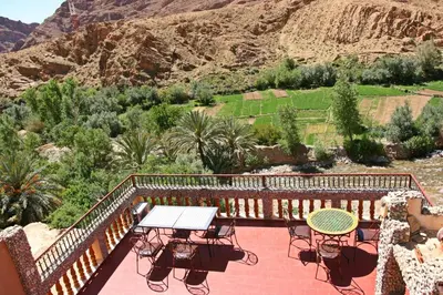 a patio with a table and chairs and a mountain at Maison d'Hôte Valentine in Tinerhir