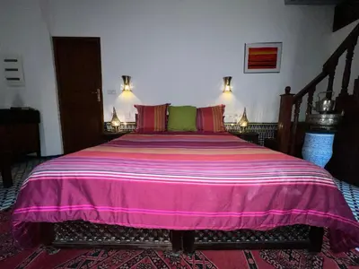 a bedroom with a large bed with a pink blanket at Riad Dezayn in Fès