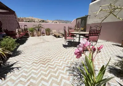 a patio with chairs and a table and flowers at Riad Dezayn in Fès