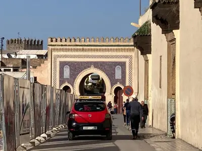 a red car driving down a street in front of a building at Dar Zin in Fès