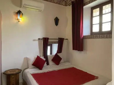 a bedroom with a bed with red pillows and a window at Dar Zin in Fès