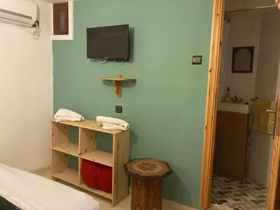 a room with a tv on a wall with a table and a stool at Dar Zin in Fès