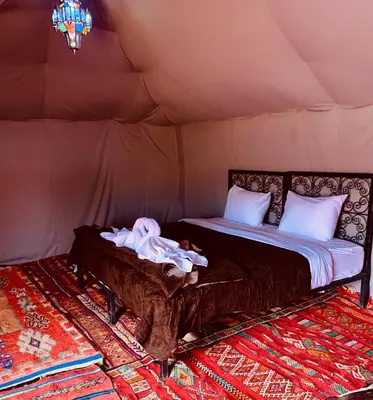 a bed in a tent with a baby laying on it at Sahara wellness camp in Merzouga