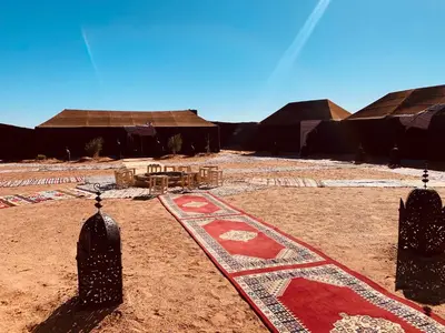 a village with a red rug on the ground at Sahara wellness camp in Merzouga