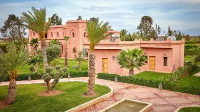 a large pink house with palm trees in front of it at Palmeraie Dar Atlas - Luxury Houses in Marrakech