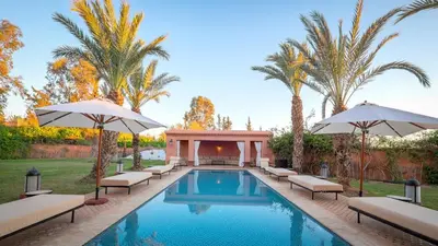 a pool with chairs and umbrellas and palm trees at Palmeraie Dar Atlas - Luxury Houses in Marrakech