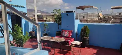 a balcony with a red chair and a table at Dar Ahl Tadla in Fès