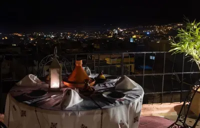 a table with plates and lamps on a balcony at night at Dar Ahl Tadla in Fès