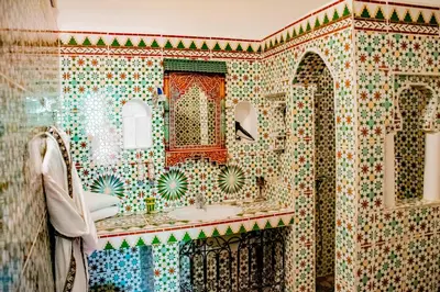 a tiled bathroom with a sink and a mirror at Le Petit Riad Maison d'hôtes in Ouarzazate