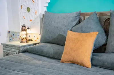 a couch with pillows and a lamp on a table at Le Petit Riad Maison d'hôtes in Ouarzazate