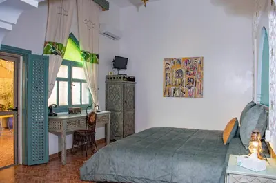a bedroom with a bed and a desk and a window at Le Petit Riad Maison d'hôtes in Ouarzazate