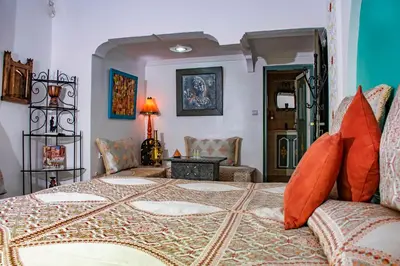 a bedroom with a large bed with orange pillows at Le Petit Riad Maison d'hôtes in Ouarzazate