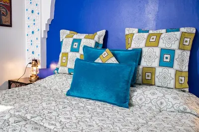 a bedroom with a bed with blue walls and pillows at Le Petit Riad Maison d'hôtes in Ouarzazate