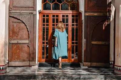 a woman in a blue dress standing in front of a door at Riad Mayfez Suites & Spa in Fès