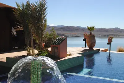 a swimming pool next to a body of water at Les Tourmalines in Ouarzazate
