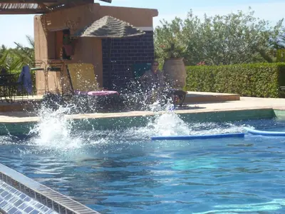 a man sitting under an umbrella in a swimming pool at Les Tourmalines in Ouarzazate