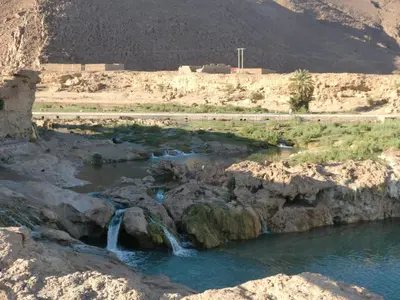 a river in the middle of a desert with waterfalls at Amoudou Lodge Camp in Tissint