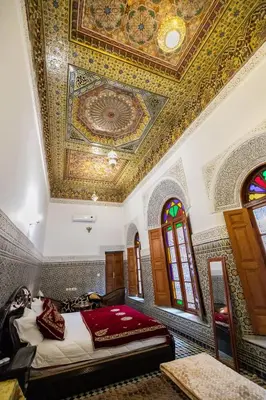 a bedroom with a ceiling with a painting on it at Riad Fes Iline in Fès