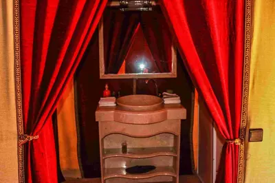 a bathroom with red curtains and a toilet and a mirror at Milky Way Desert Camp in Merzouga