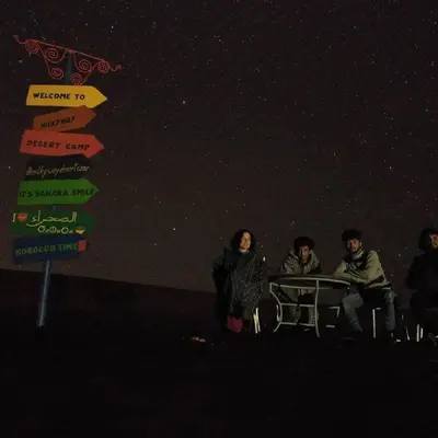 a group of people sitting at a table in front of a street sign at Milky Way Desert Camp in Merzouga