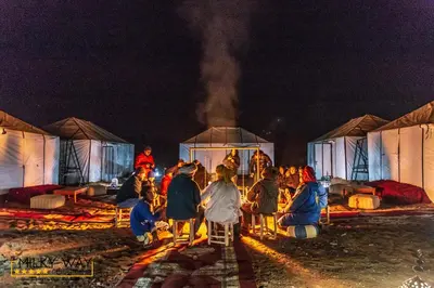 a group of people standing in front of tents at night at Milky Way Desert Camp in Merzouga