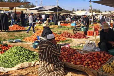 a man sitting in front of a market with vegetables at La Vallée des Dunes - Auberge, randonnées et circuits in Merzouga