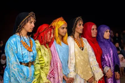 a group of young women dressed in colorful clothing at La Vallée des Dunes - Auberge, randonnées et circuits in Merzouga