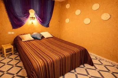a bedroom with a bed in a room with purple curtains at La Vallée des Dunes - Auberge, randonnées et circuits in Merzouga
