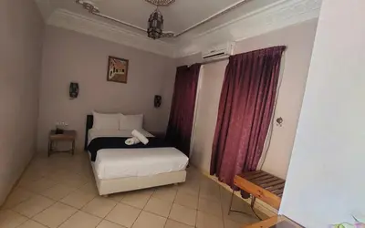 a small bedroom with a bed and red curtains at Kasbat Aferdou in Er Rachidia