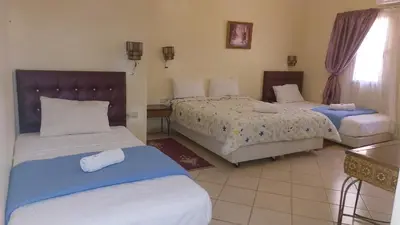 a hotel room with two beds and a table at Kasbat Aferdou in Er Rachidia