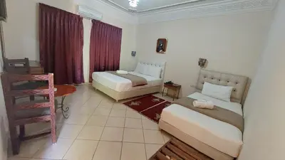 a room with two beds and a table and a chair at Kasbat Aferdou in Er Rachidia