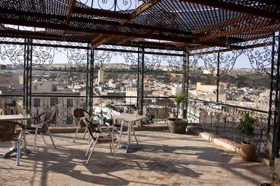 a patio with tables and chairs and a view of a city at Hotel Bab Boujloud in Fès
