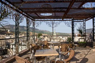 a patio with tables and chairs on a balcony at Hotel Bab Boujloud in Fès