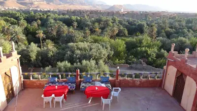 a patio with tables and chairs and a view of the mountains at Kasbah Omari in Tinerhir