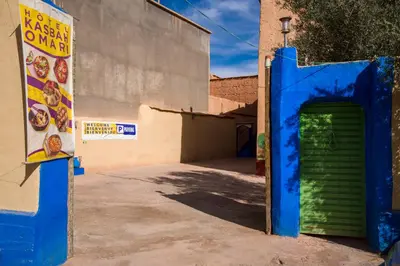 a building with a blue and green door in a parking lot at Kasbah Omari in Tinerhir