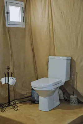 a bathroom with a toilet and a window at Camel Trips Luxury Camp in Merzouga