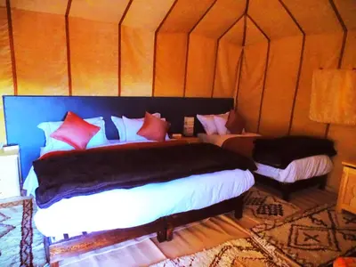 a bedroom with two beds in a tent at Camel Trips Luxury Camp in Merzouga