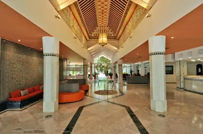 a lobby of a hotel with orange furniture and a ceiling at Hôtel Volubilis in Fès