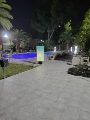a park at night with a sign on the sidewalk at Hôtel Volubilis in Fès