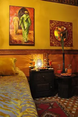 a bedroom with a bed and a table with a mirror at Riad La Maison Verte in Fès
