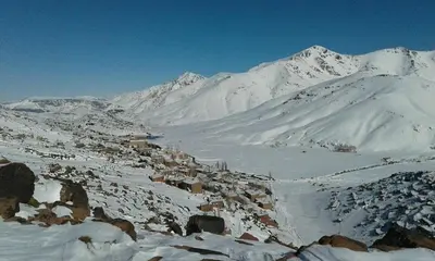 a snow covered mountain with a town in the foreground at Chalet tizrag in Oukkainrdem