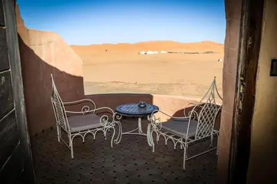 a porch with two chairs and a table and a desert at Dune House in Merzouga