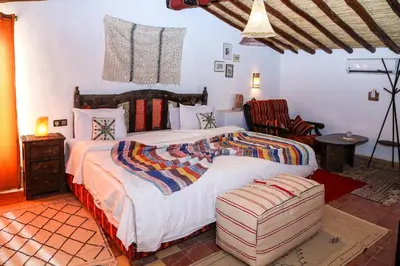 a bedroom with a large bed and a chair at Dune House in Merzouga